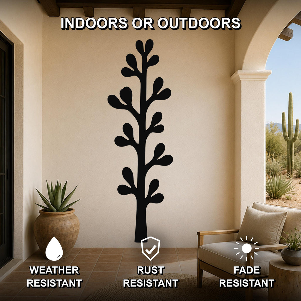 Black metal olive branch wall art with leafy cutouts, mounted on a beige outdoor patio wall above a wooden chair.