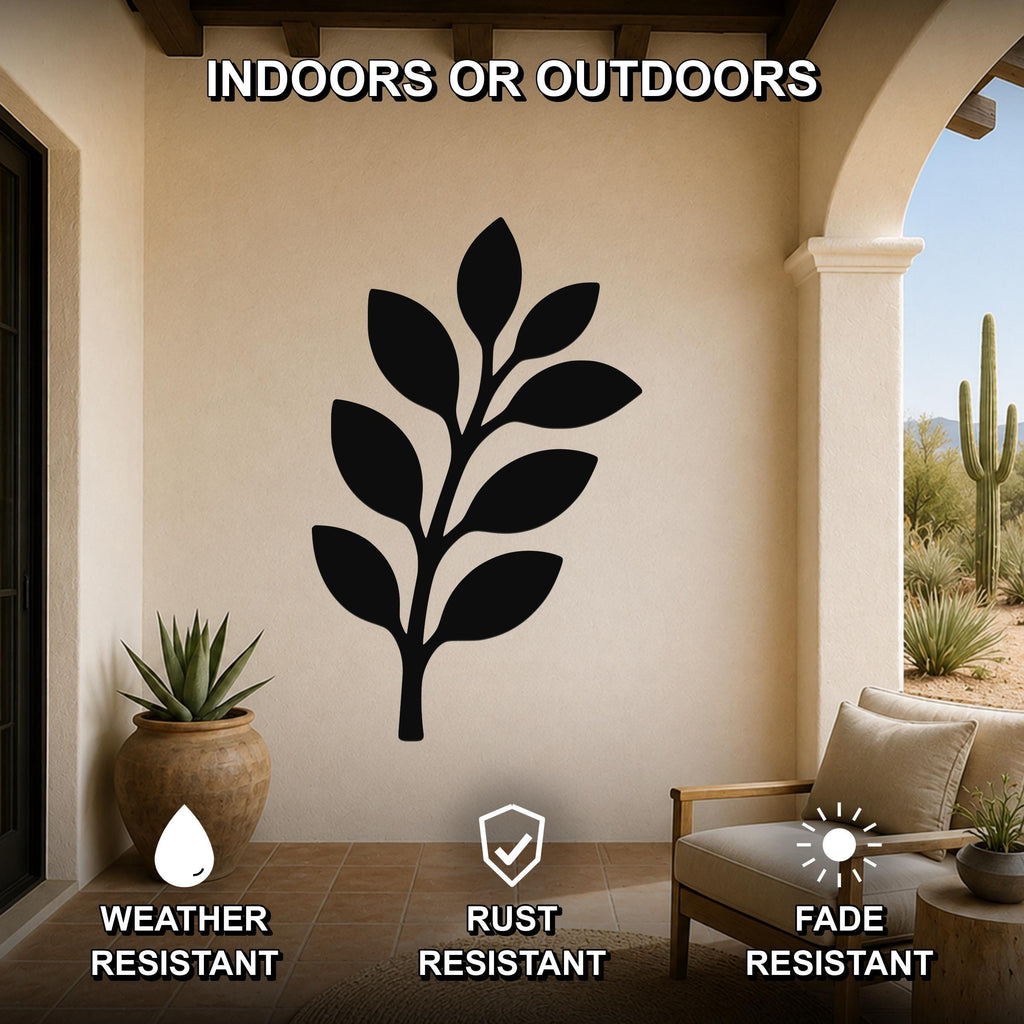Black metal olive branch wall art with leaf cutouts, mounted on a beige outdoor patio wall above a wooden chair and potted succulent.