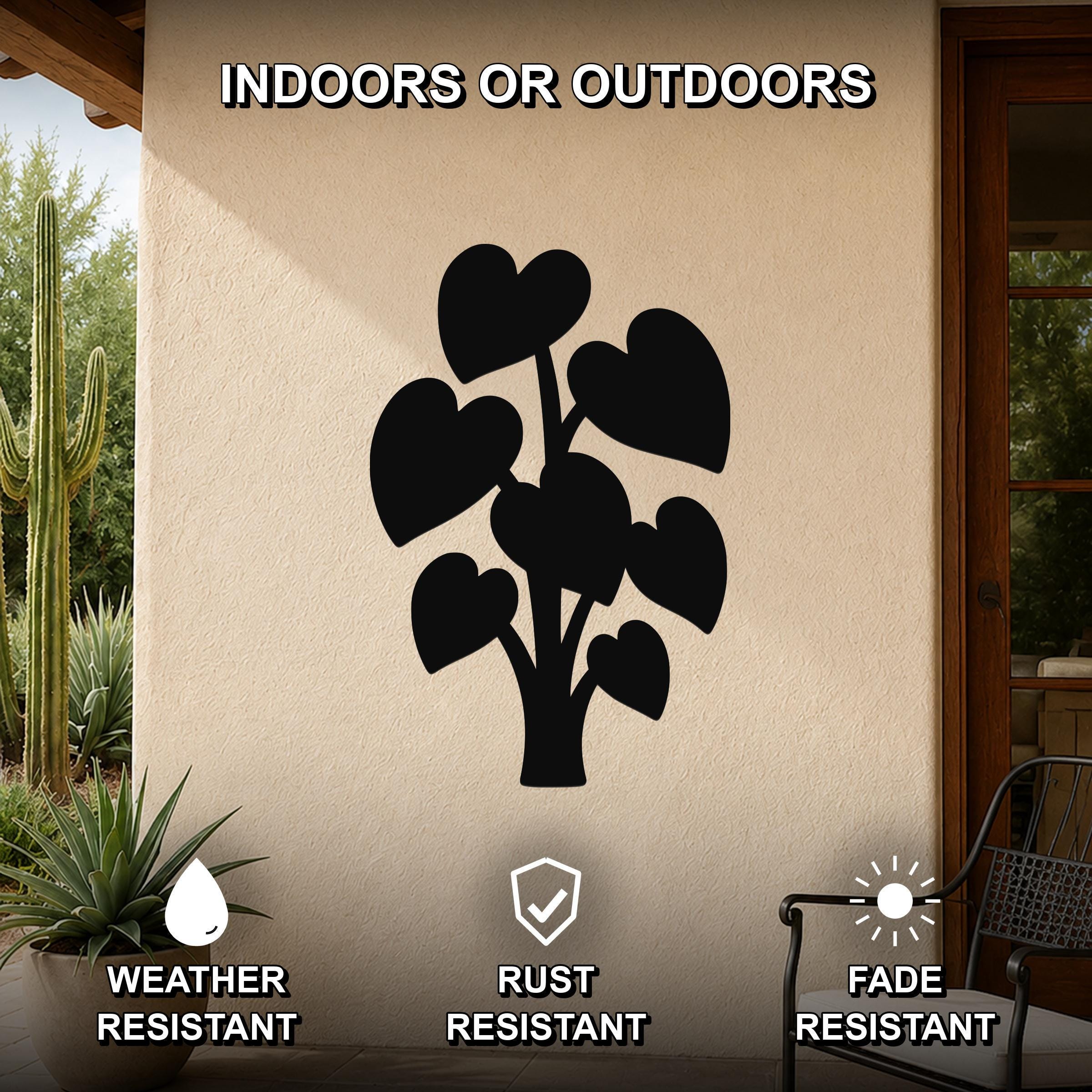 Black metal wall art in the silhouette of an elephant ear plant with heart-shaped leaves, mounted on an outdoor patio wall.