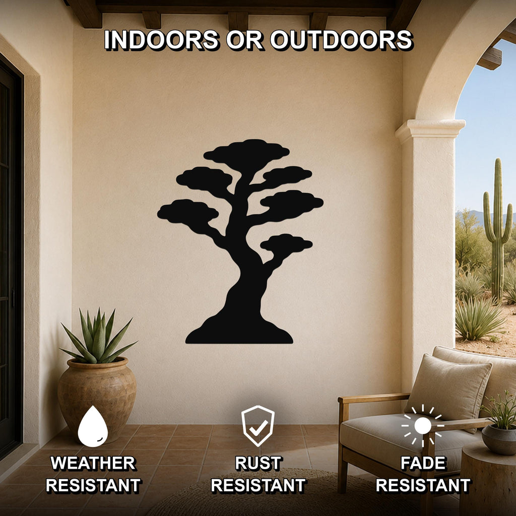 Black metal bonsai tree wall art silhouette mounted on a beige outdoor patio wall, weather resistant, rust resistant, and fade resistant, with a potted succulent and lounge chair nearby.