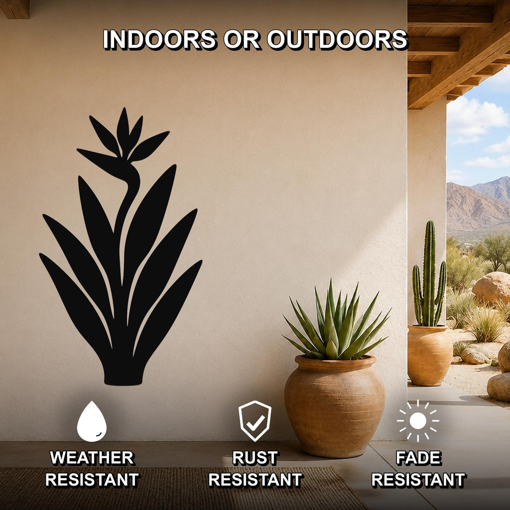 Black metal Bird of Paradise wall art silhouette mounted on a beige outdoor wall, displayed above a potted succulent on a patio with mountains in the background.