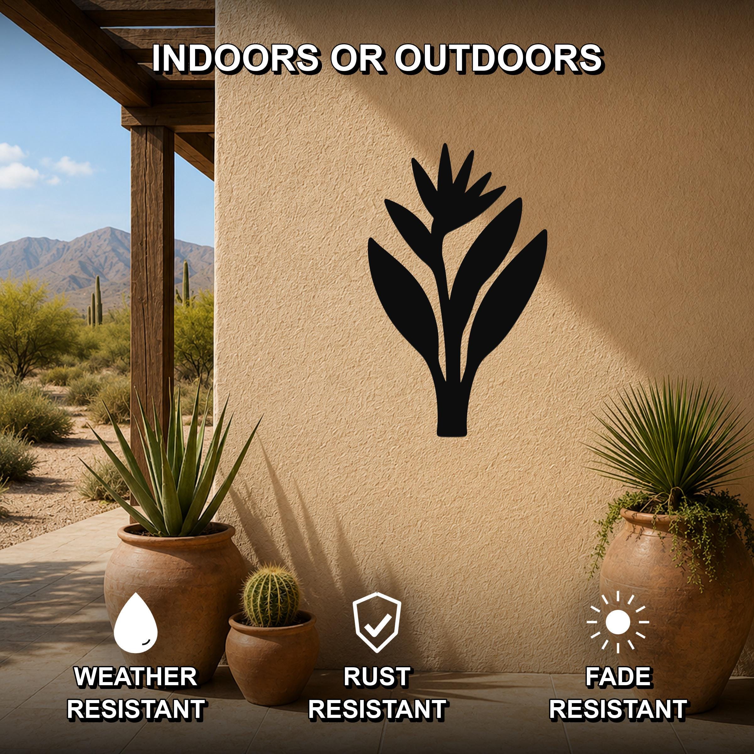 Black metal Bird of Paradise wall art silhouette mounted on a stucco outdoor wall, displayed on a patio with potted plants and desert scenery in the background.