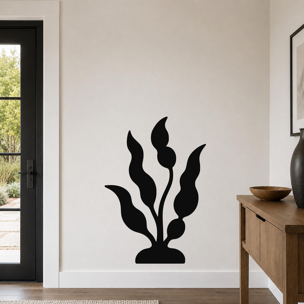 Black metal wall art in a kelp or seaweed silhouette design, mounted on a light-colored wall in a modern entryway near a door and console table.
