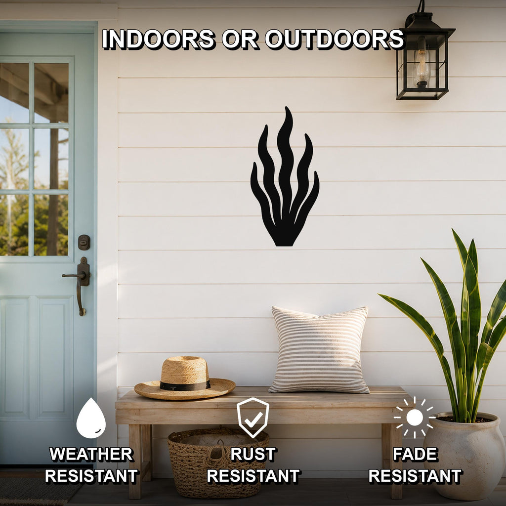 Black metal kelp wall art with flowing seaweed cutouts, mounted on a white shiplap wall above a wooden bench in a coastal porch setting.