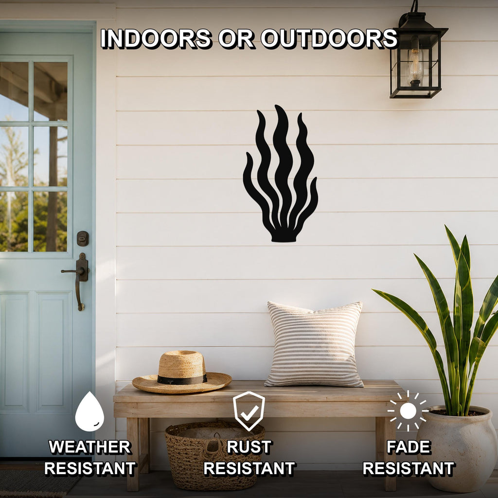 Black metal kelp wall art with flowing frond cutouts, mounted on a white shiplap wall above a wooden bench on a porch.