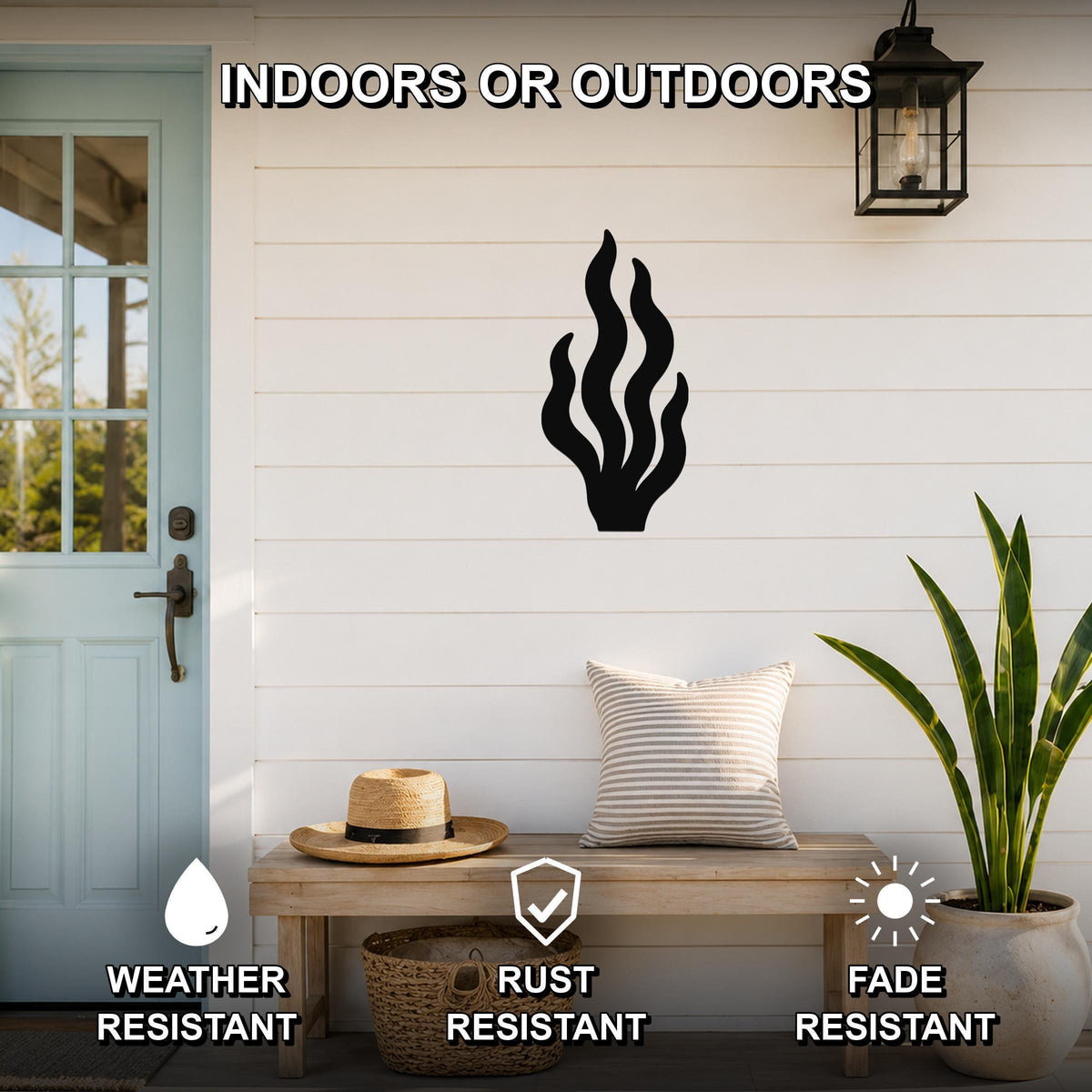 Black metal kelp wall art with flowing seaweed cutouts, mounted on a white shiplap wall above a wooden bench on a porch.