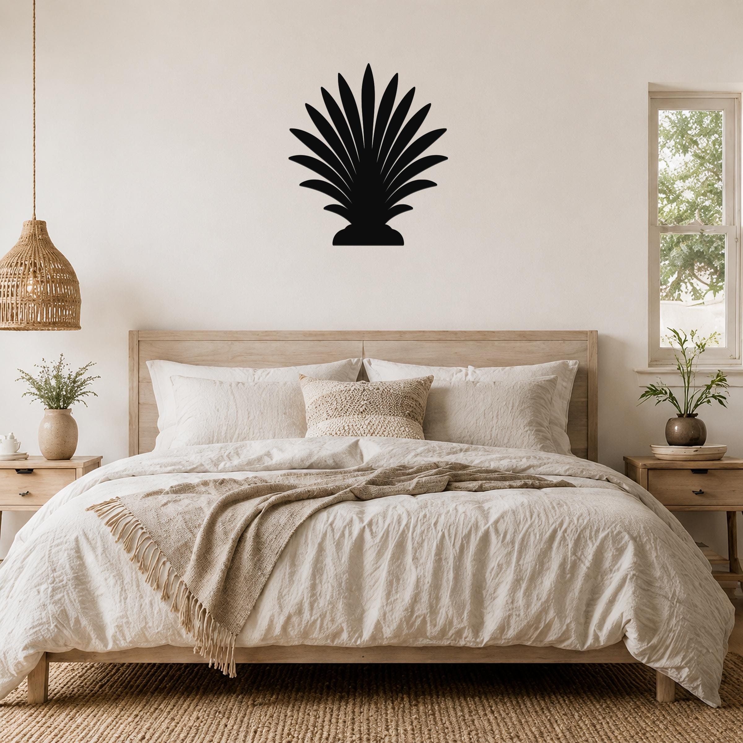 Black metal palm tree wall art with fan-shaped fronds, mounted above a wooden bed in a neutral bedroom.