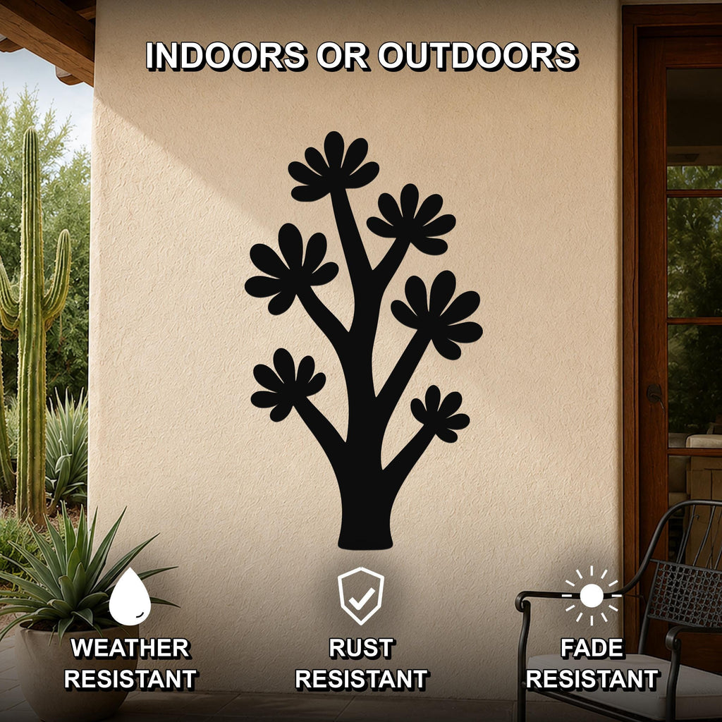 Black metal wall art in a tree silhouette with flower cutouts, mounted on an outdoor patio wall above a potted plant.