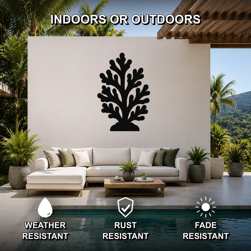 Black metal coral wall art with branching cutouts, mounted on a white outdoor wall above a sofa in a patio living area.