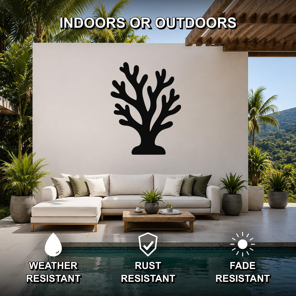 Black metal coral wall art with branching cutouts, mounted on a white outdoor wall above a sofa in a patio living area.