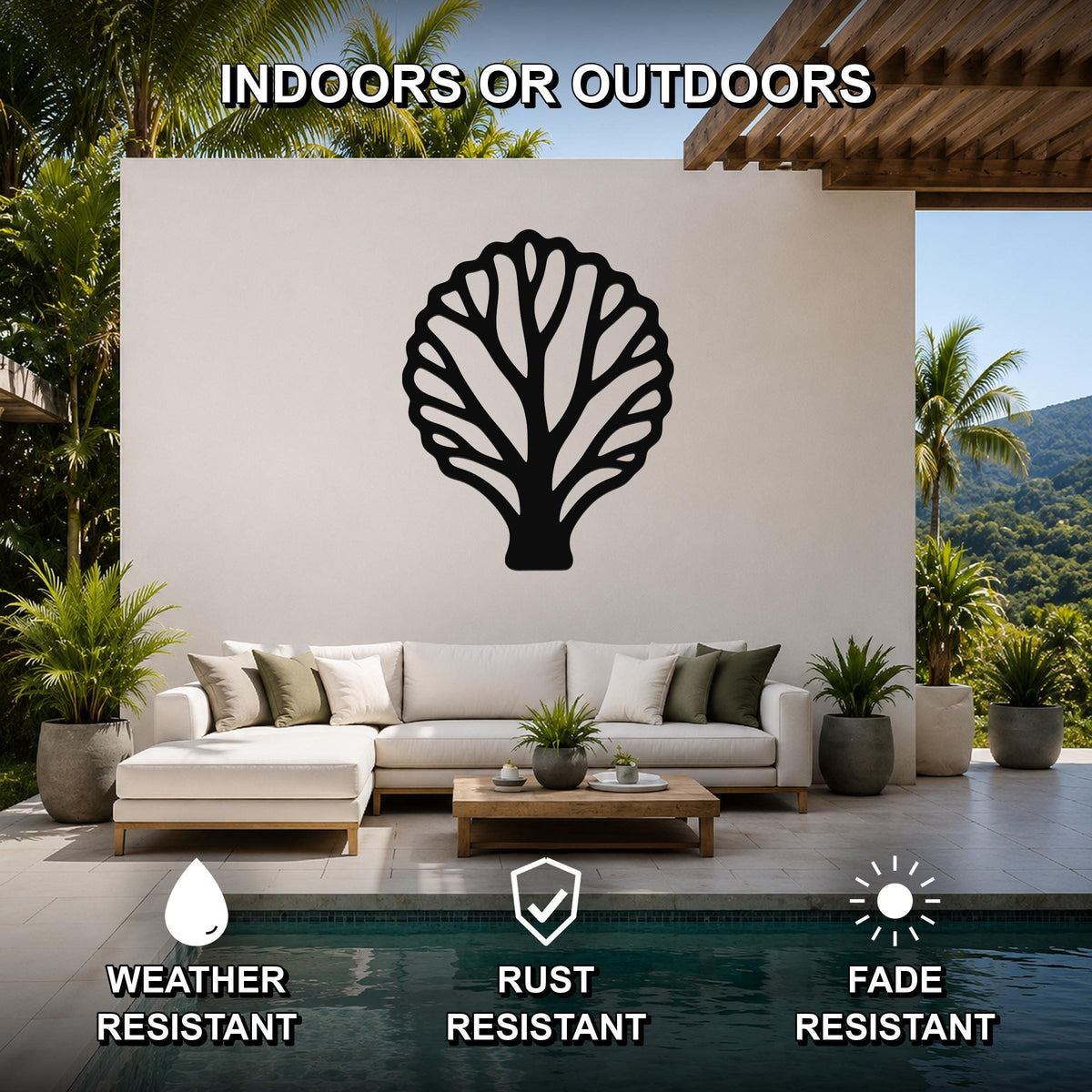 Black metal fan coral wall art with intricate cutout branches, mounted on a white outdoor wall above a sofa in a patio setting.