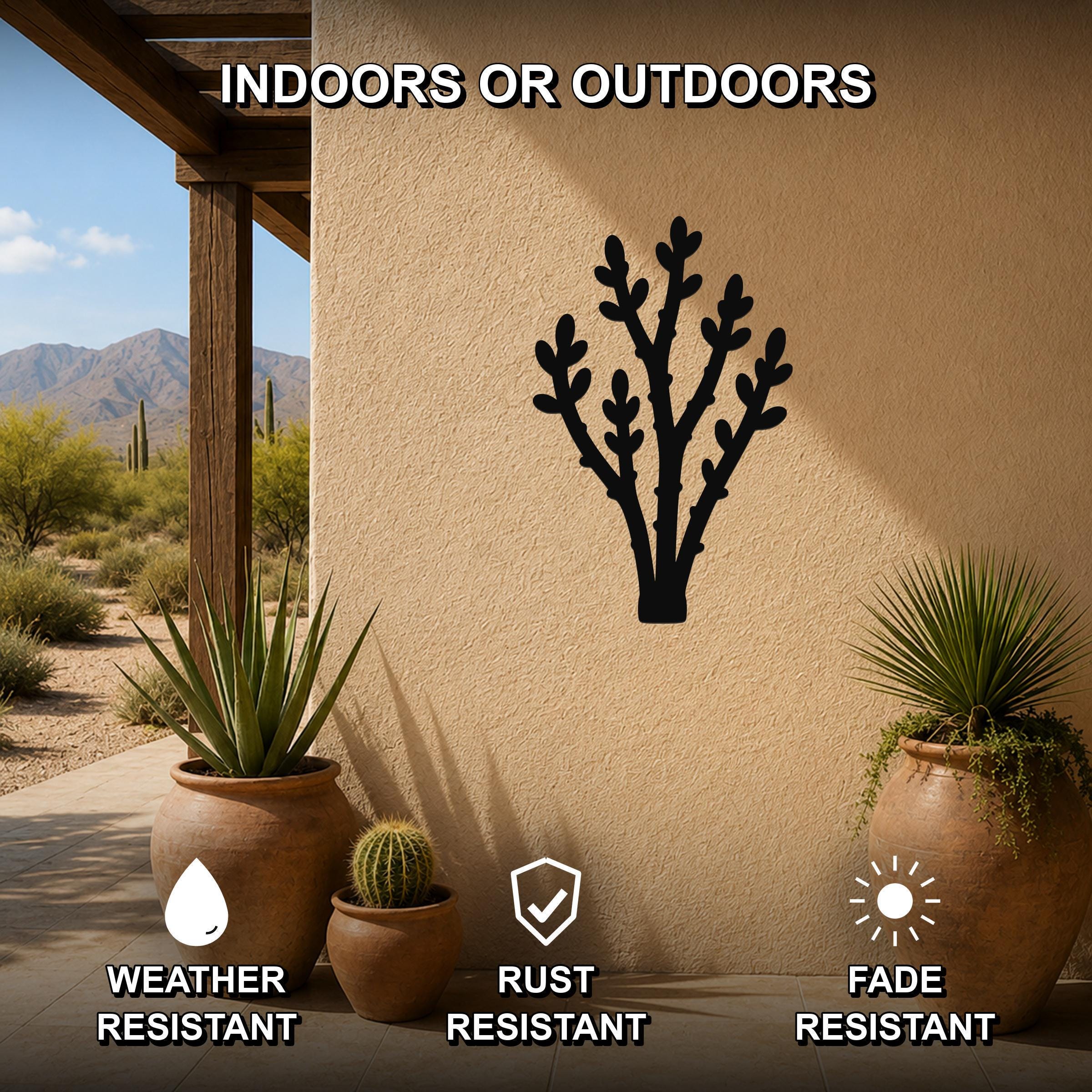 Black metal desert branch wall art with leafy cutouts, mounted on an outdoor patio wall above potted succulents.