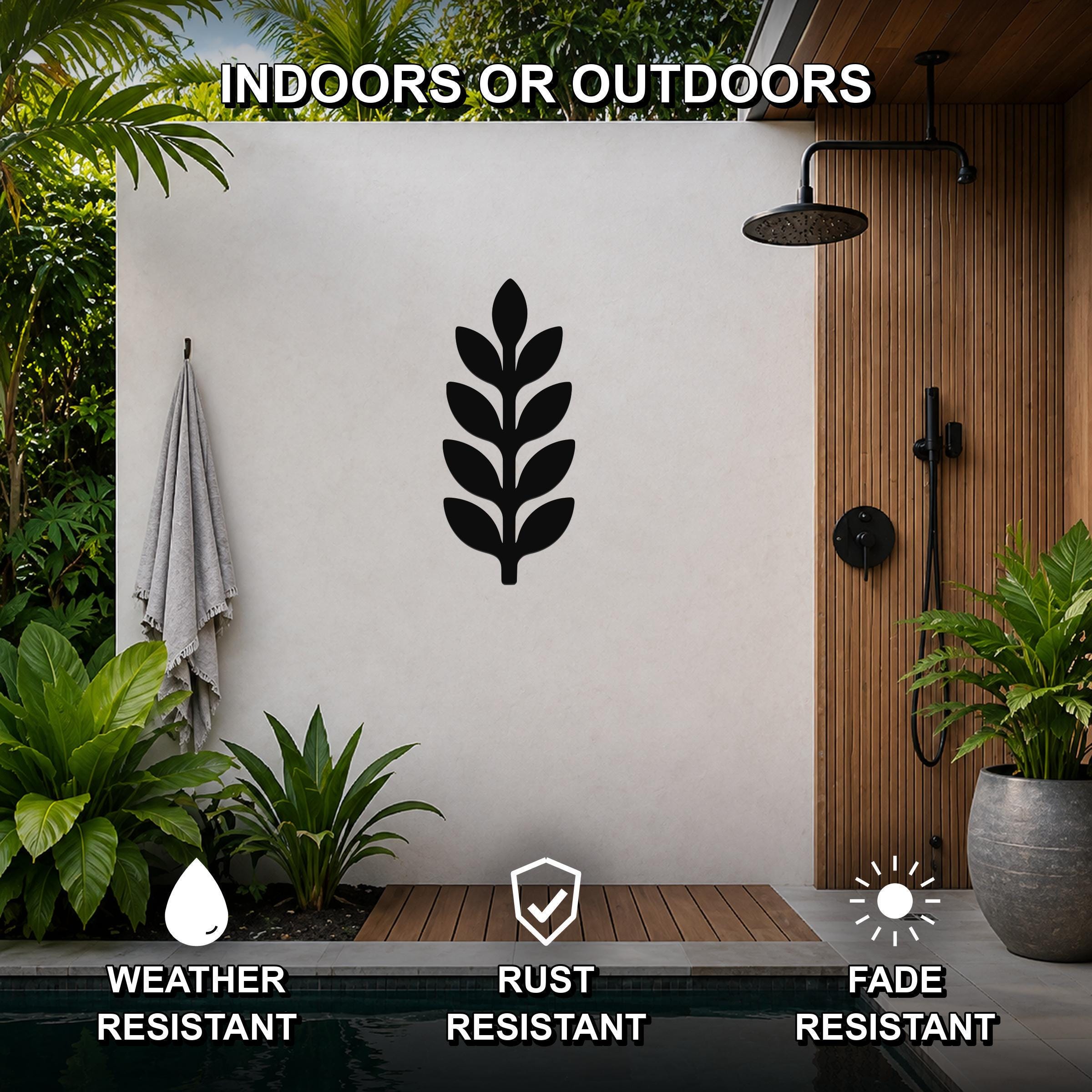 Black metal botanical sprig wall art with leaf cutouts, mounted on a white outdoor wall beside a shower and pool, weather, rust, and fade resistant.