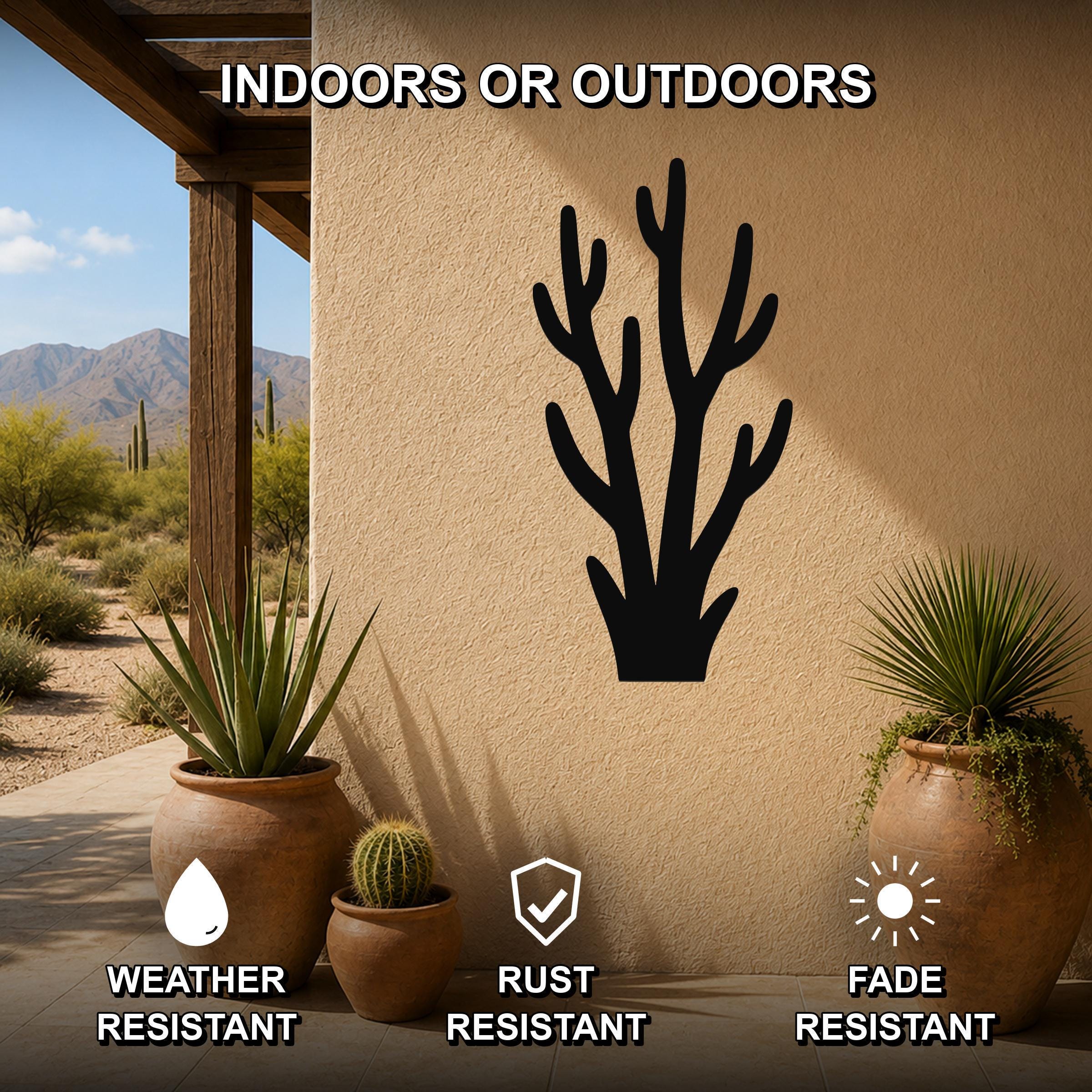 Black metal branch wall art silhouette mounted on a beige outdoor wall, displayed on a patio with potted plants and desert scenery in the background.