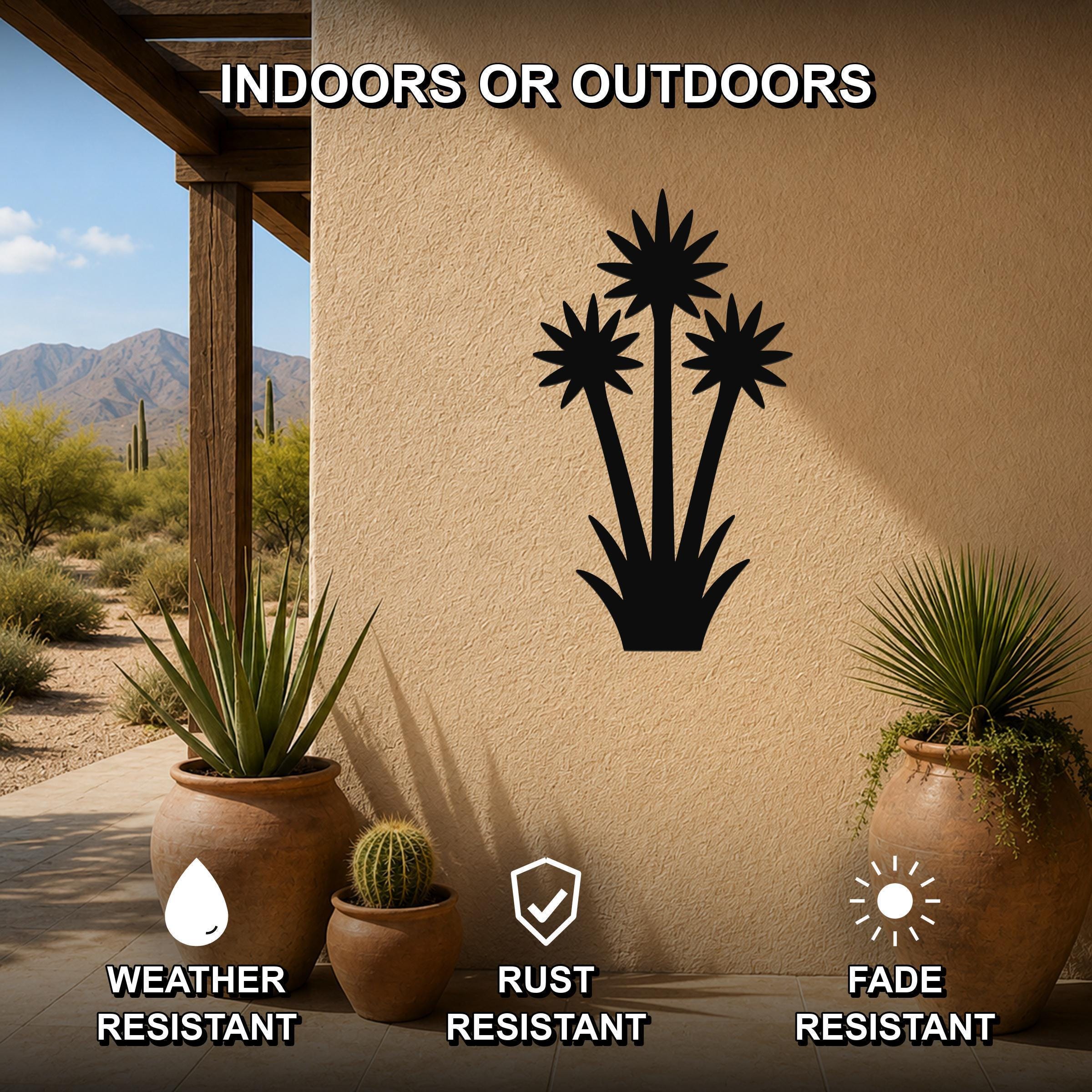 Black metal yucca wall art with three blooming flower cutouts, mounted on a stucco outdoor wall above potted plants on a patio.