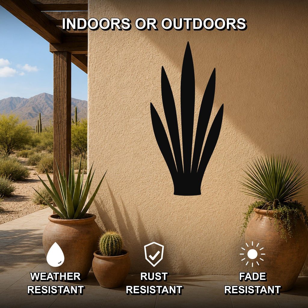 Black metal agave plant wall art silhouette mounted on a beige outdoor wall, displayed on a patio with potted plants and desert scenery in the background.