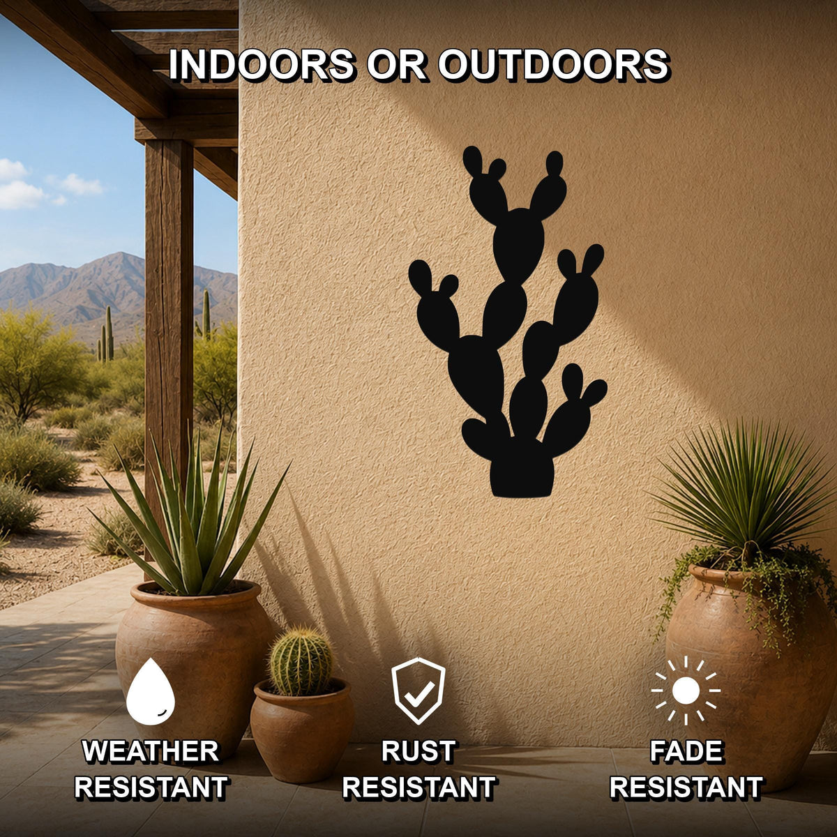 Black metal cactus wall art with a silhouette cutout of a prickly pear cactus, mounted on a beige outdoor wall above potted plants on a patio.