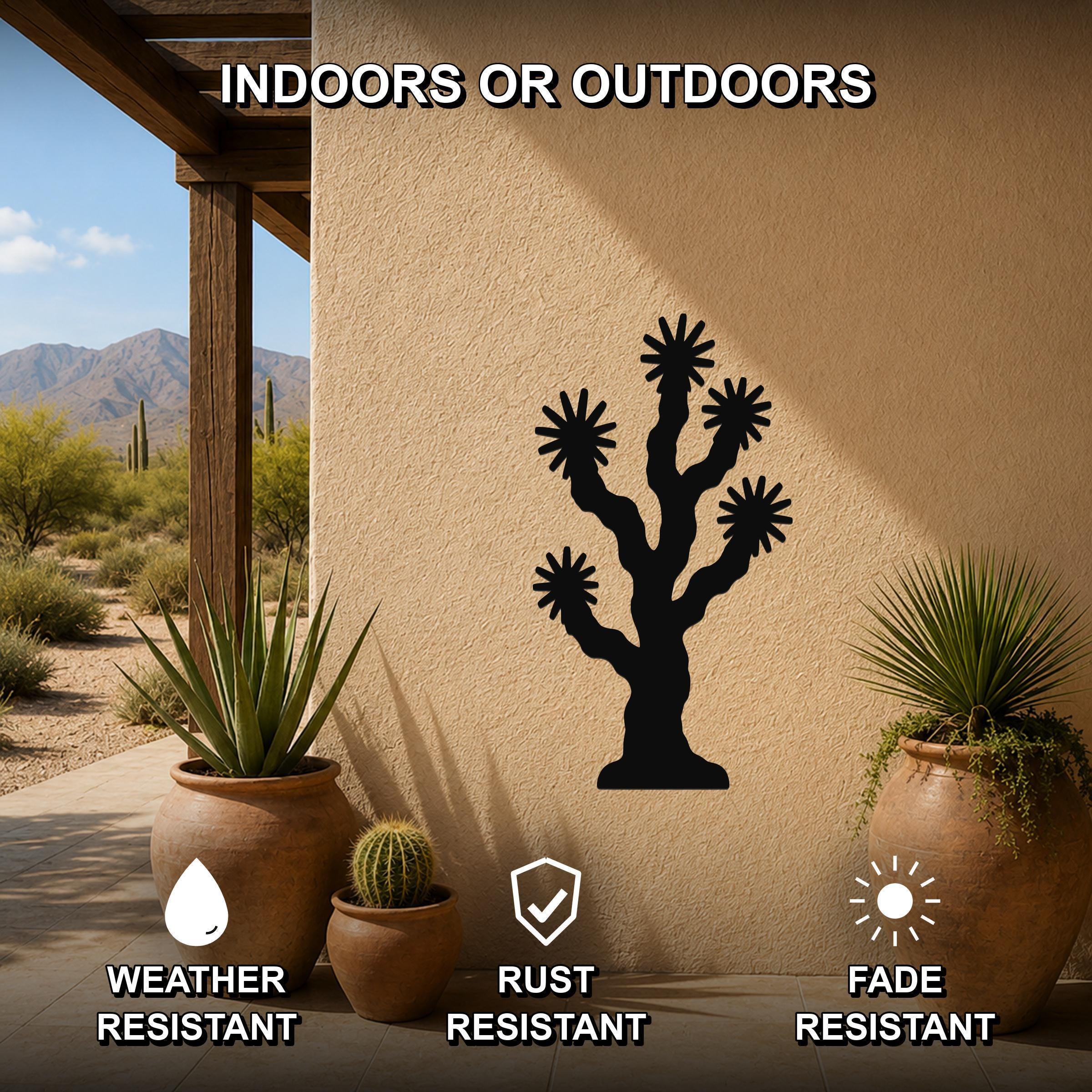 Black metal Joshua tree wall art with starburst cutouts, mounted on an outdoor patio wall between potted plants.