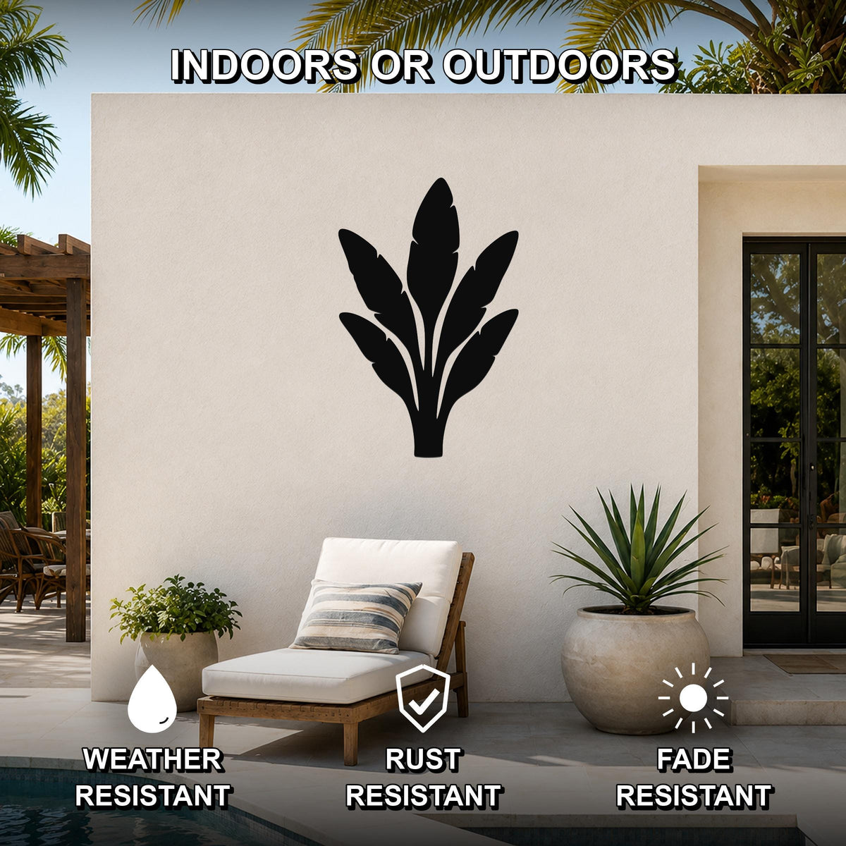 Black metal banana plant wall art with leaf cutouts, mounted on an outdoor patio wall above a lounge chair.