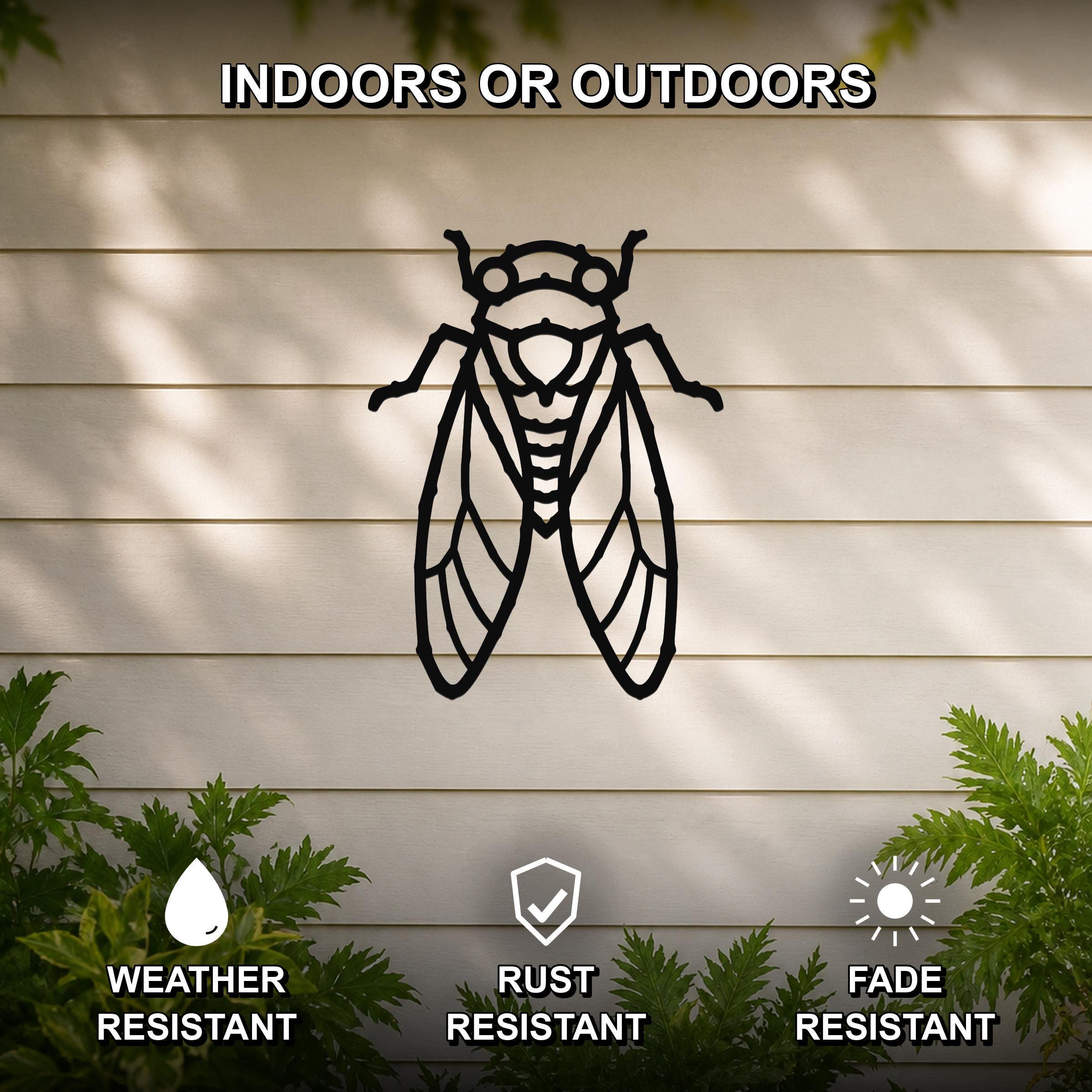 Black metal cicada wall art with detailed wing and body cutouts, mounted on a light-colored outdoor wall with greenery below.