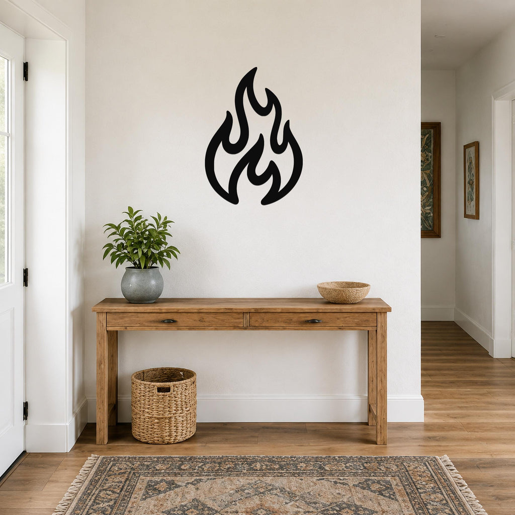Black metal flame wall art with flowing, abstract cutout shapes, mounted on a white wall above a wooden console table in a hallway.