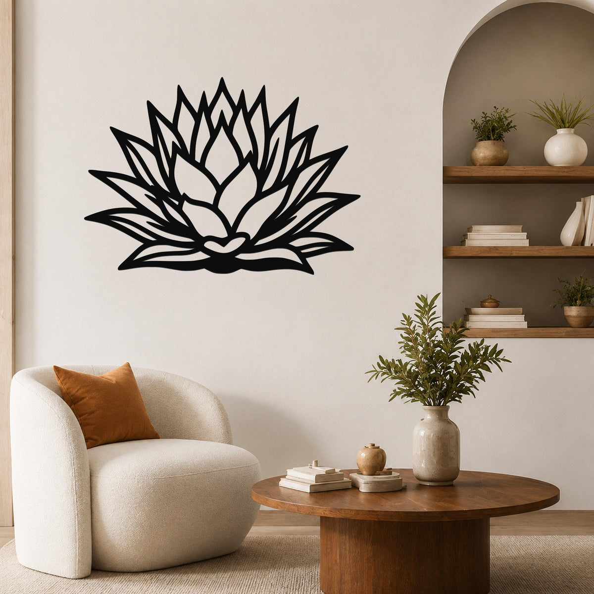 Black metal agave wall sculpture with layered leaf cutouts, mounted on a living room wall above a round wooden coffee table.