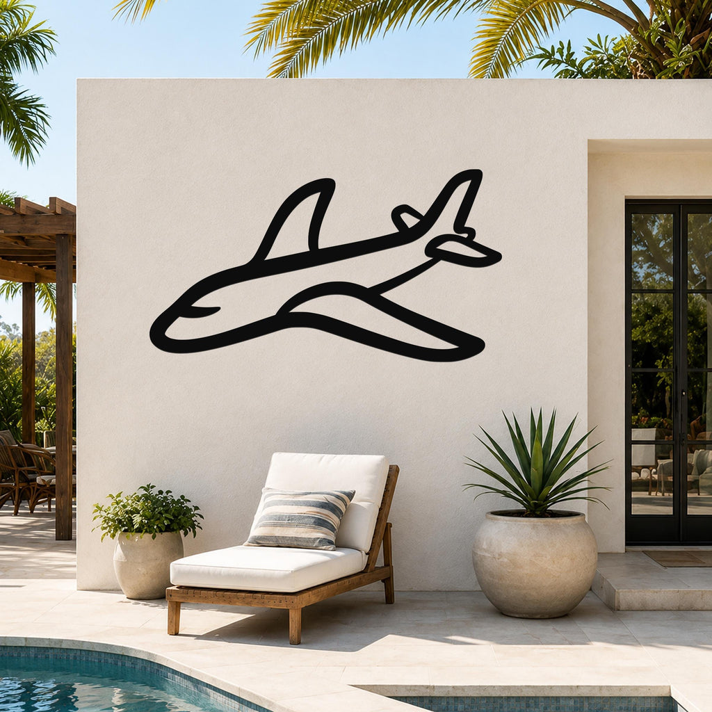 Black metal airplane silhouette wall art mounted on an outdoor patio wall above a lounge chair, with palm trees and a pool in the background.