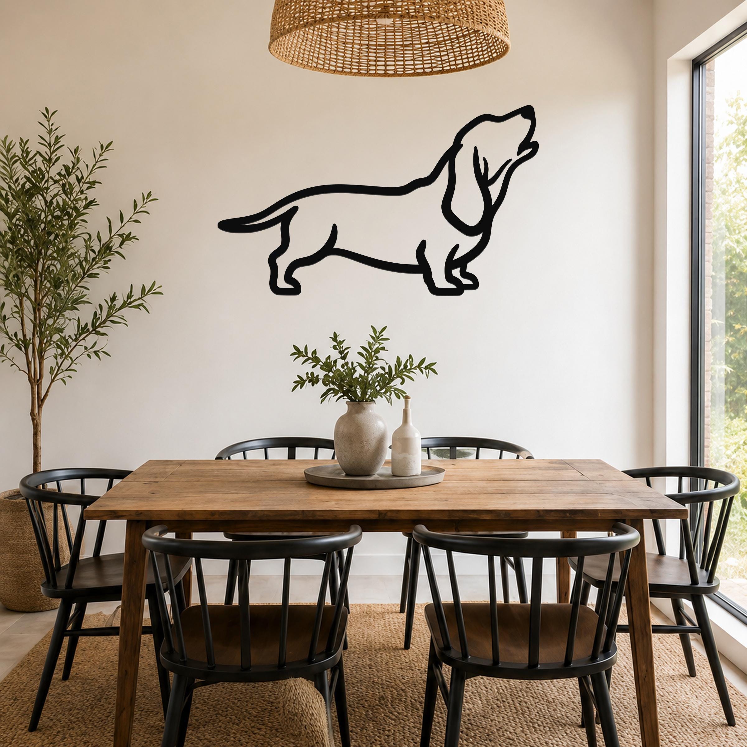 Black metal Basset Hound silhouette wall art mounted on a white wall above a wooden dining table in a bright, modern dining room.