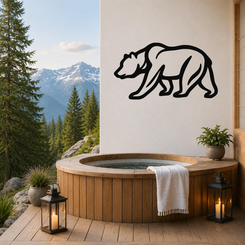 Black metal bear silhouette wall art mounted on a white wall above a wooden hot tub on a mountain-view deck.