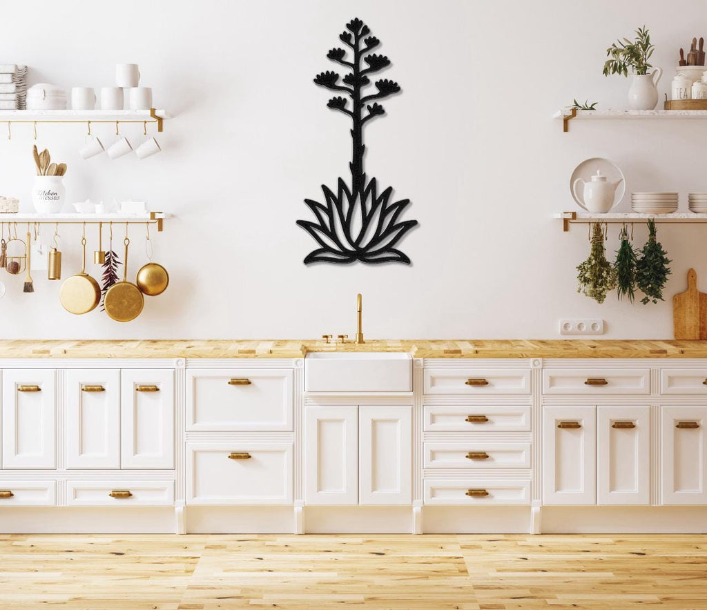 Black metal agave wall art with a blooming flower and leaf cutout design, mounted on a kitchen wall above a wooden countertop.