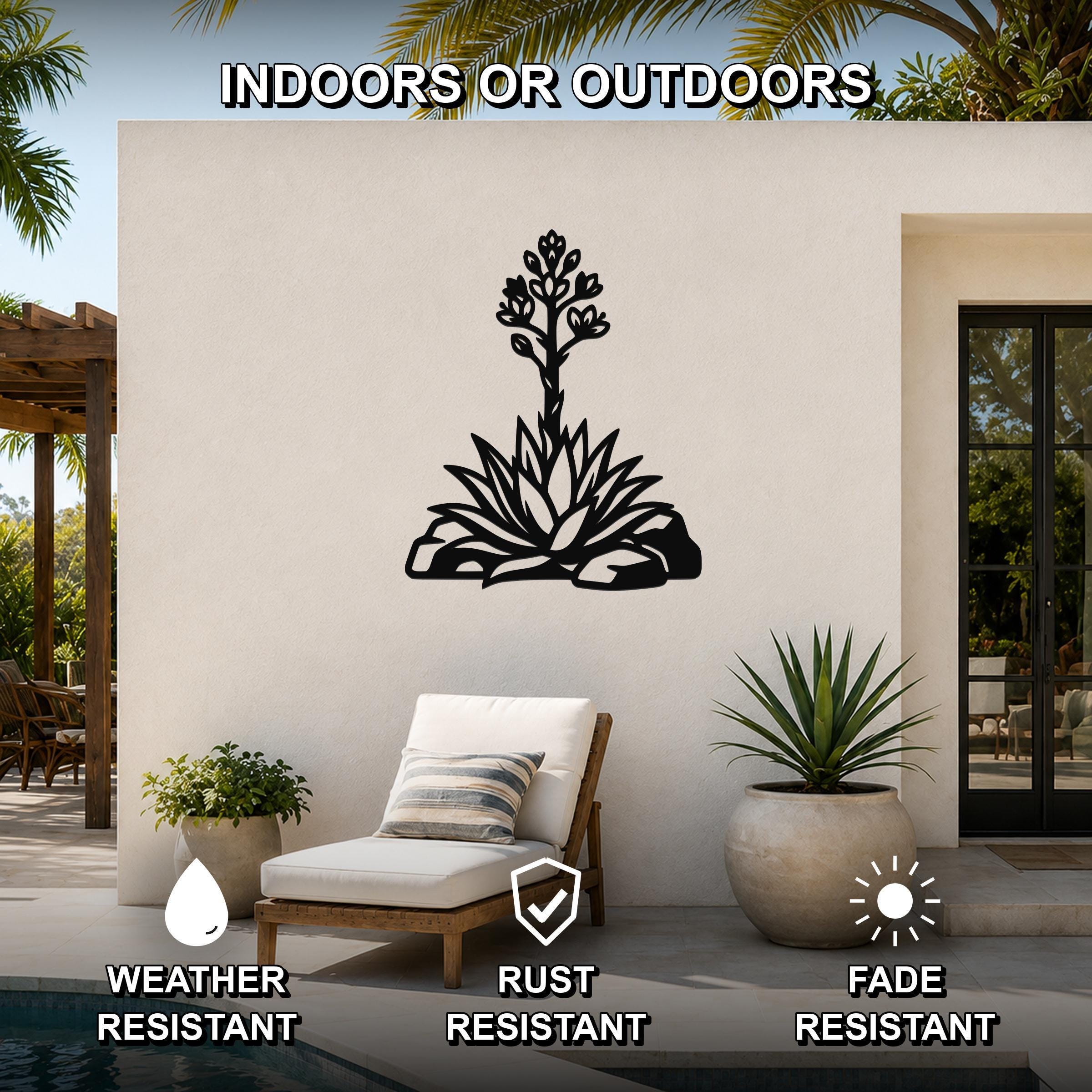 Black metal agave wall art with blooming flower and leaf cutouts, mounted on an outdoor patio wall above a lounge chair.