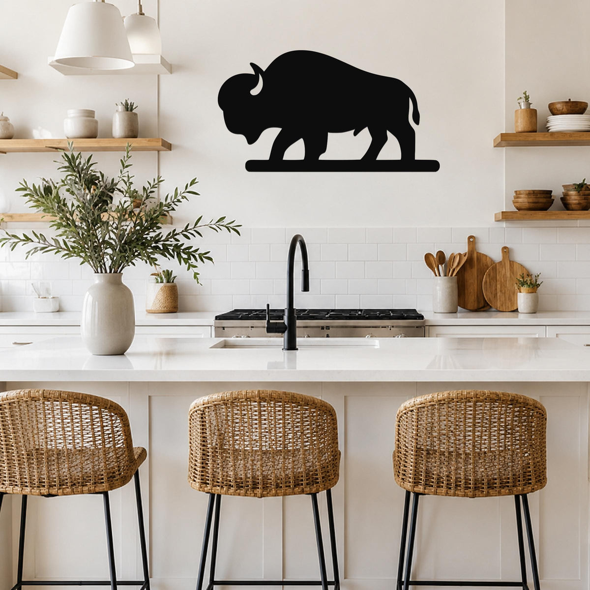 Black metal bison silhouette wall art mounted above a kitchen counter, featuring a solid cutout design with visible horns and tail, displayed in a modern kitchen with white cabinets and wooden shelves.