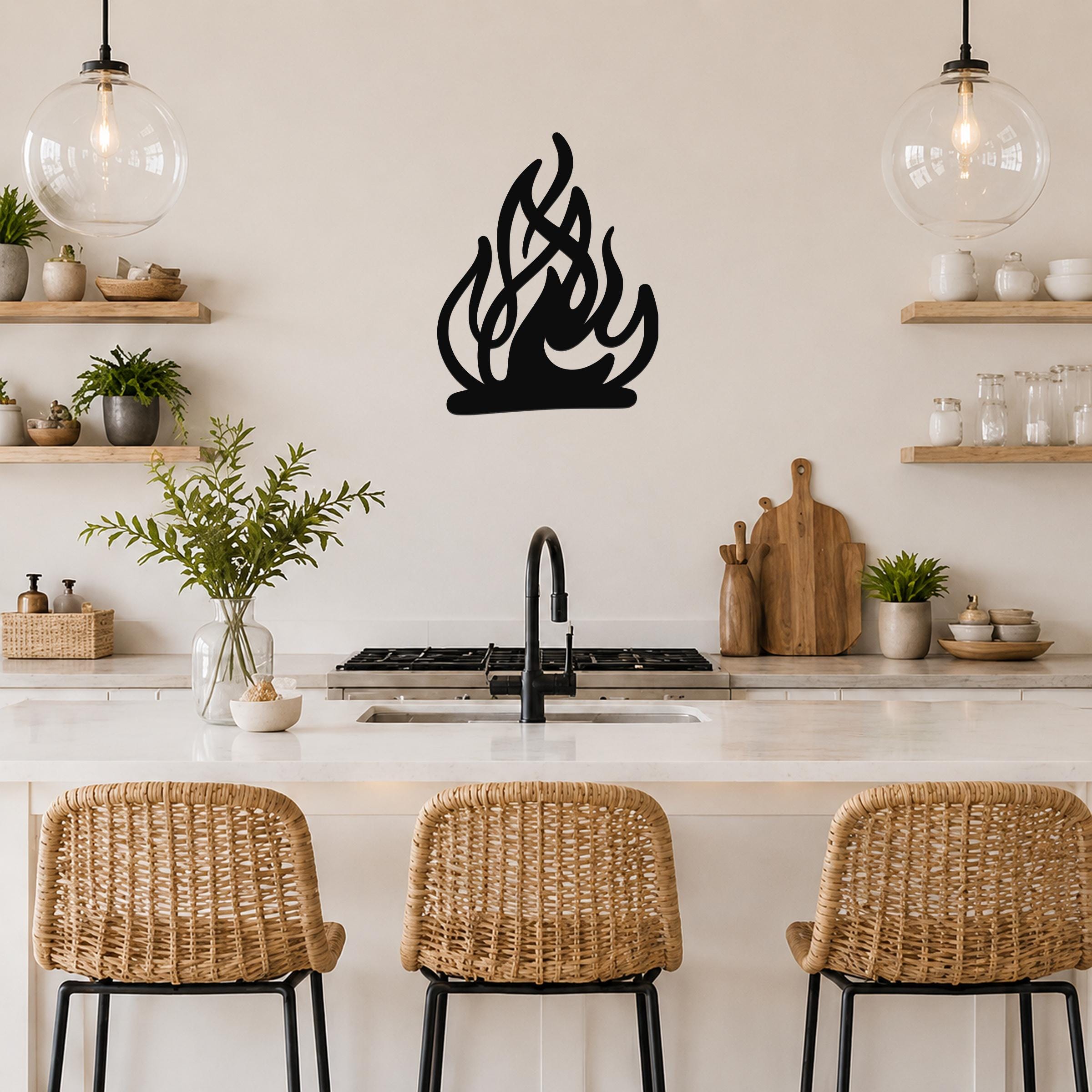 Black metal flame silhouette wall art mounted on a kitchen wall above a counter, with visible cutout details and a modern, rustic aesthetic.