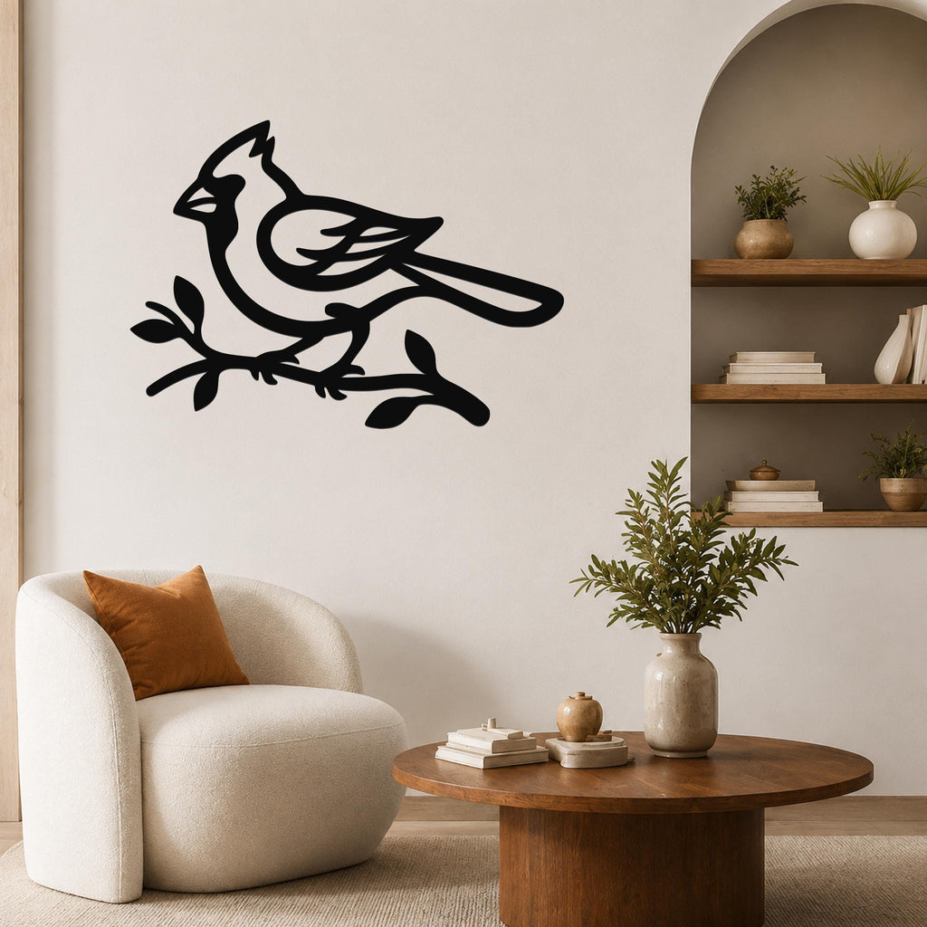 Black metal cardinal wall art in silhouette, perched on a branch, mounted on a living room wall above a white armchair.