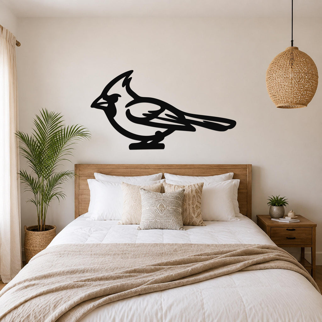 Black metal cardinal wall art in silhouette style, mounted above a bed in a bedroom with wooden furniture and a woven pendant light.