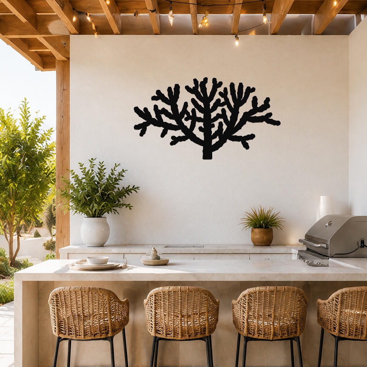 Black metal Cholla cactus wall art silhouette with branching cutouts, mounted on a white outdoor wall above a kitchen counter.