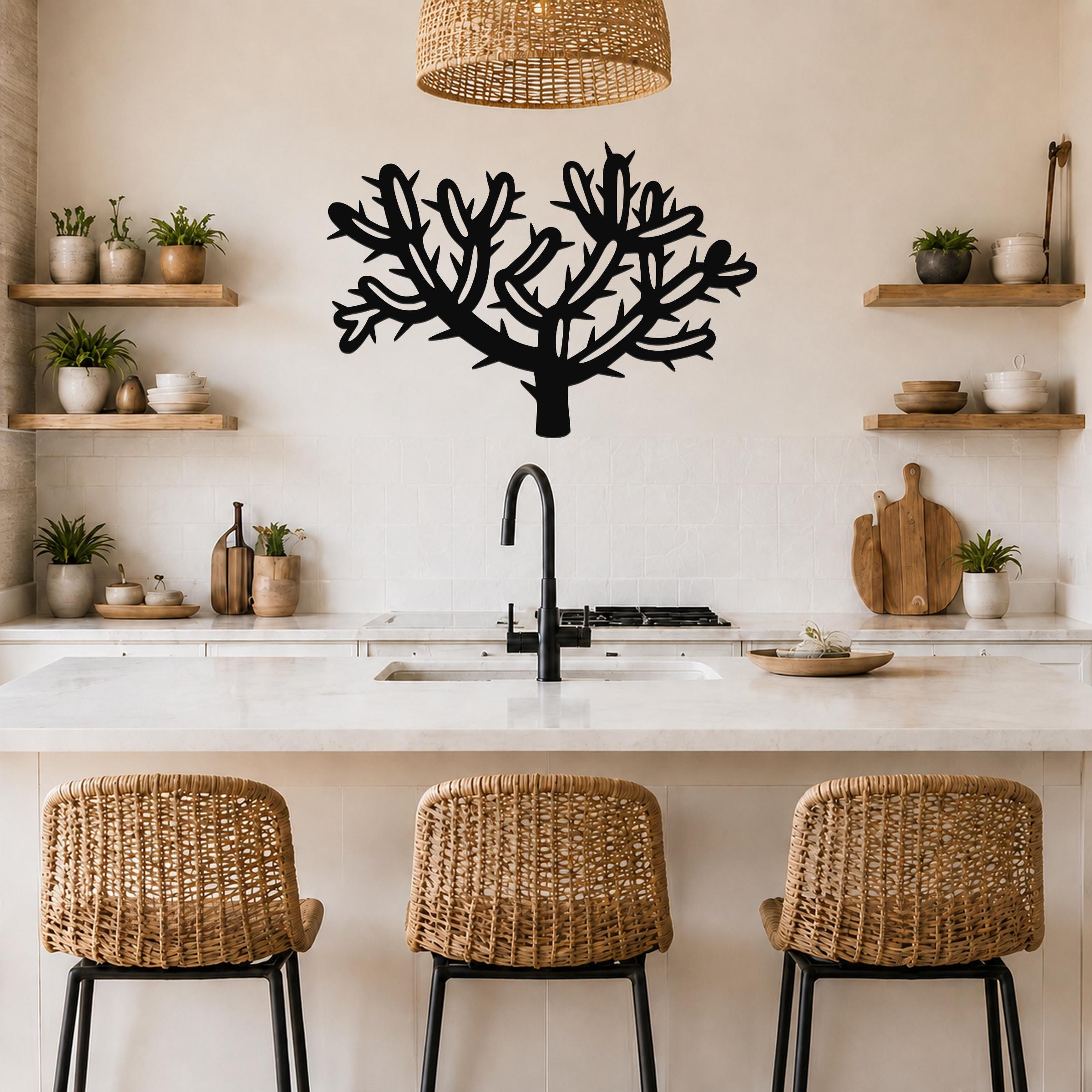Black metal cholla cactus wall art with branching cutouts, mounted above a kitchen counter in a neutral-toned kitchen.