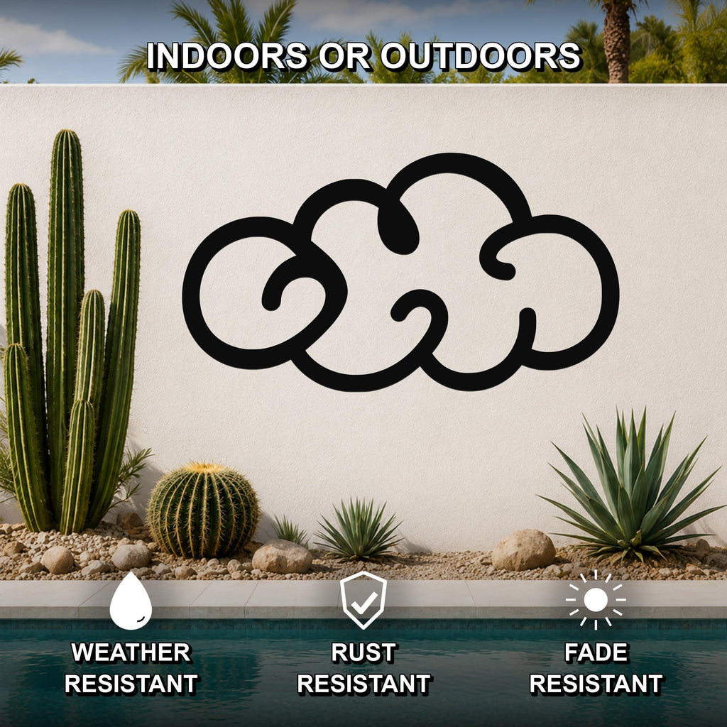 Black metal cloud wall art with a cutout design, mounted on an outdoor wall above a pool, surrounded by cacti and desert plants.