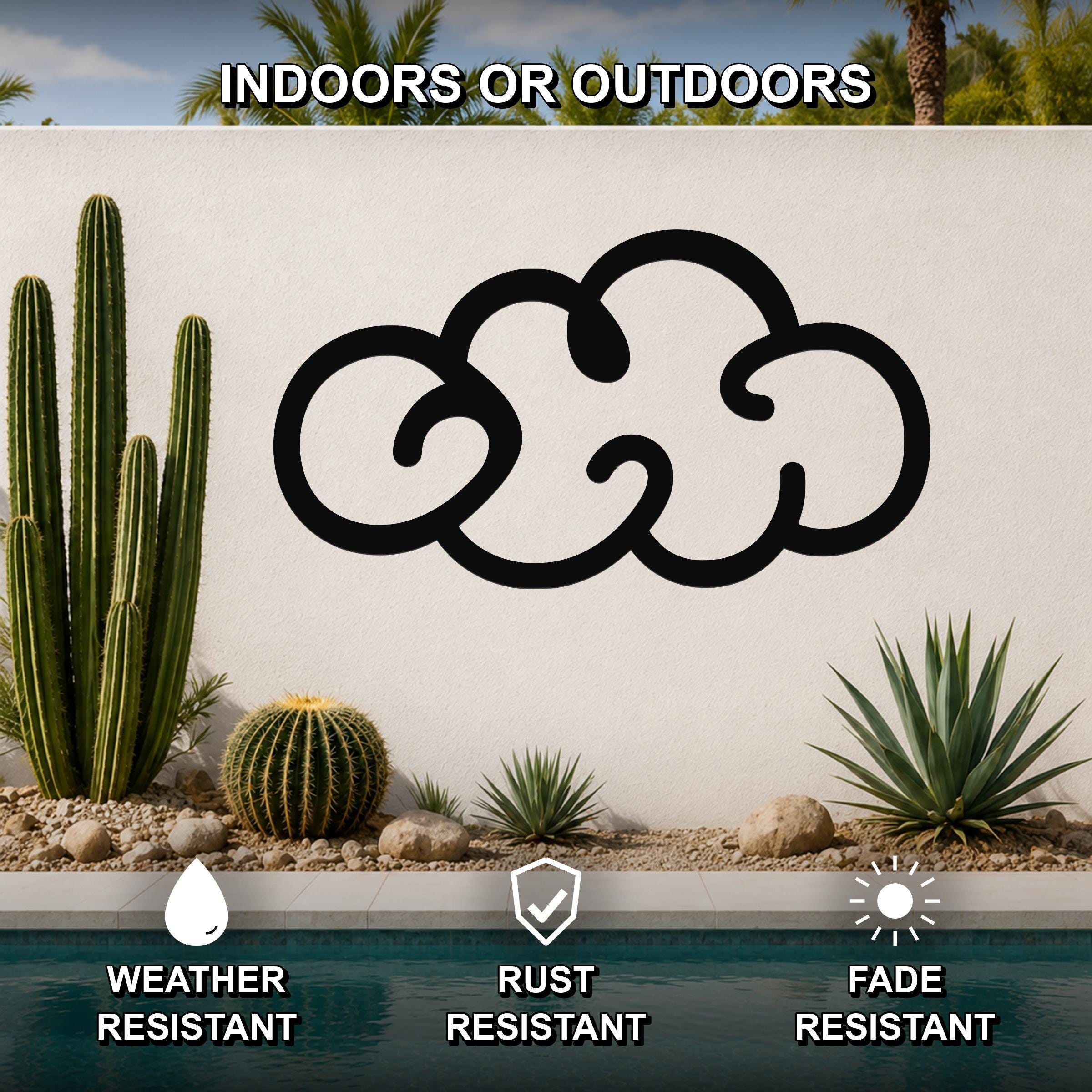 Black metal cloud wall art with a cutout design, mounted on an outdoor wall above a pool, surrounded by cacti and desert plants.