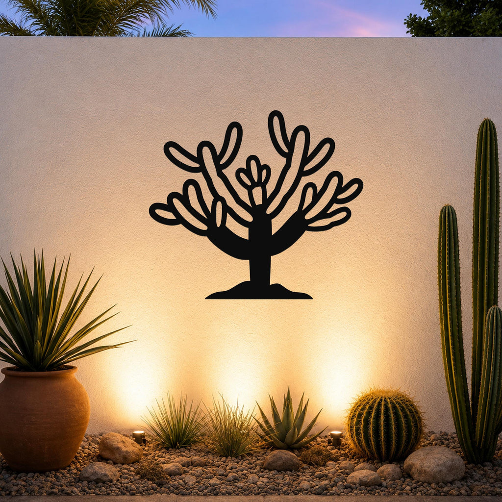 Black metal Cholla cactus wall art with branching cutouts, mounted on a white outdoor wall above a desert garden with potted plants and ground lights.