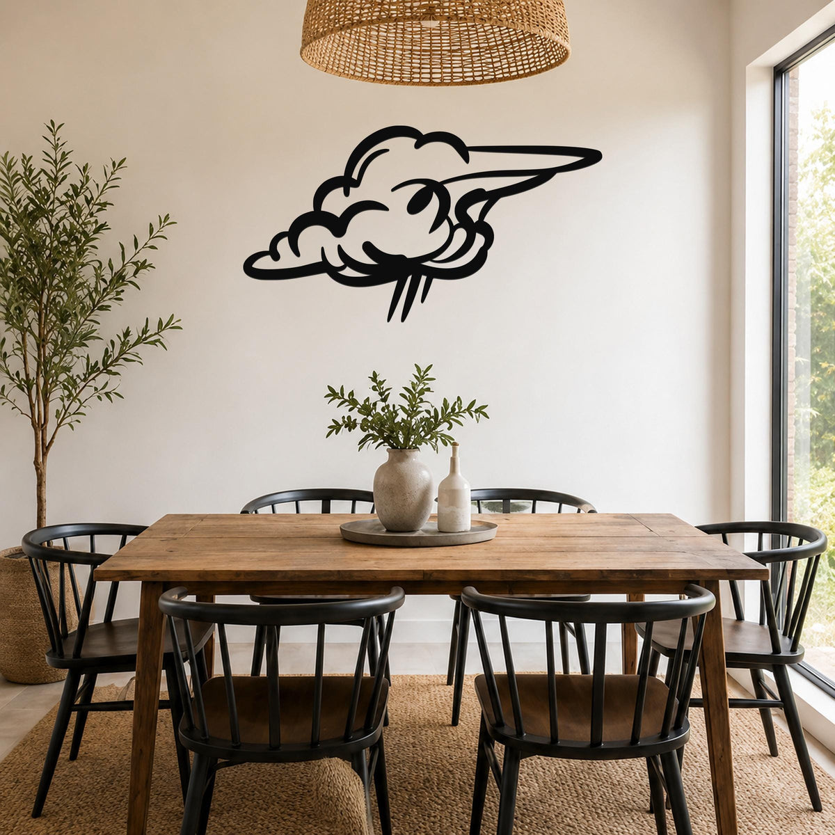 Black metal cloud wall art with a stylized, flowing silhouette, mounted on a white wall above a wooden dining table in a bright, modern dining room.