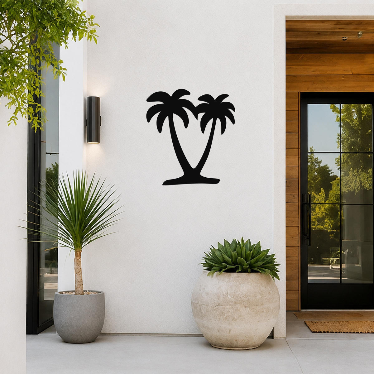 Black metal palm tree wall art with two silhouetted trees, mounted on a white exterior wall beside a glass door and potted plants.