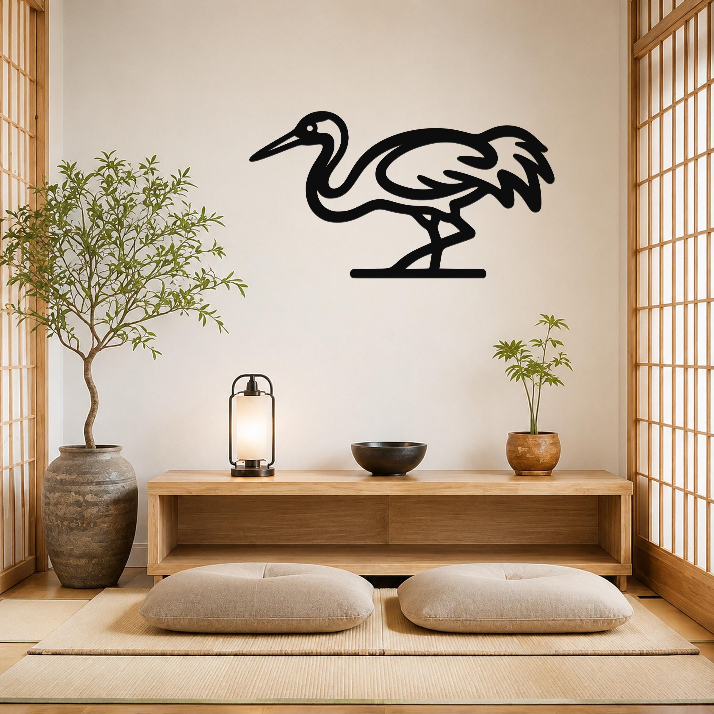 Black metal crane wall art with a silhouette design, mounted on a wall above a wooden console in a minimalist room with tatami mats and plants.