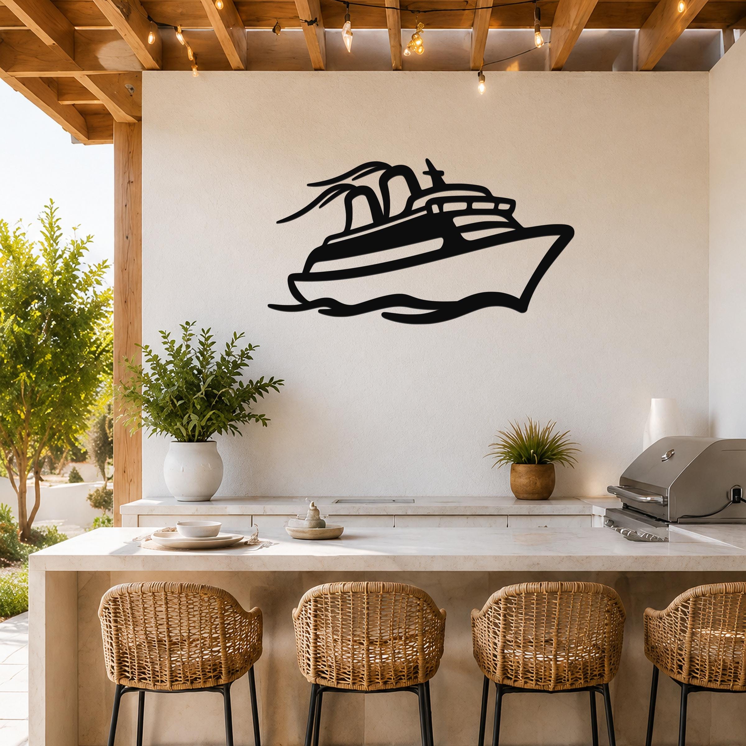 Black metal cruise ship wall art with motion-line cutouts, mounted on a white wall above a kitchen counter in an outdoor patio setting.