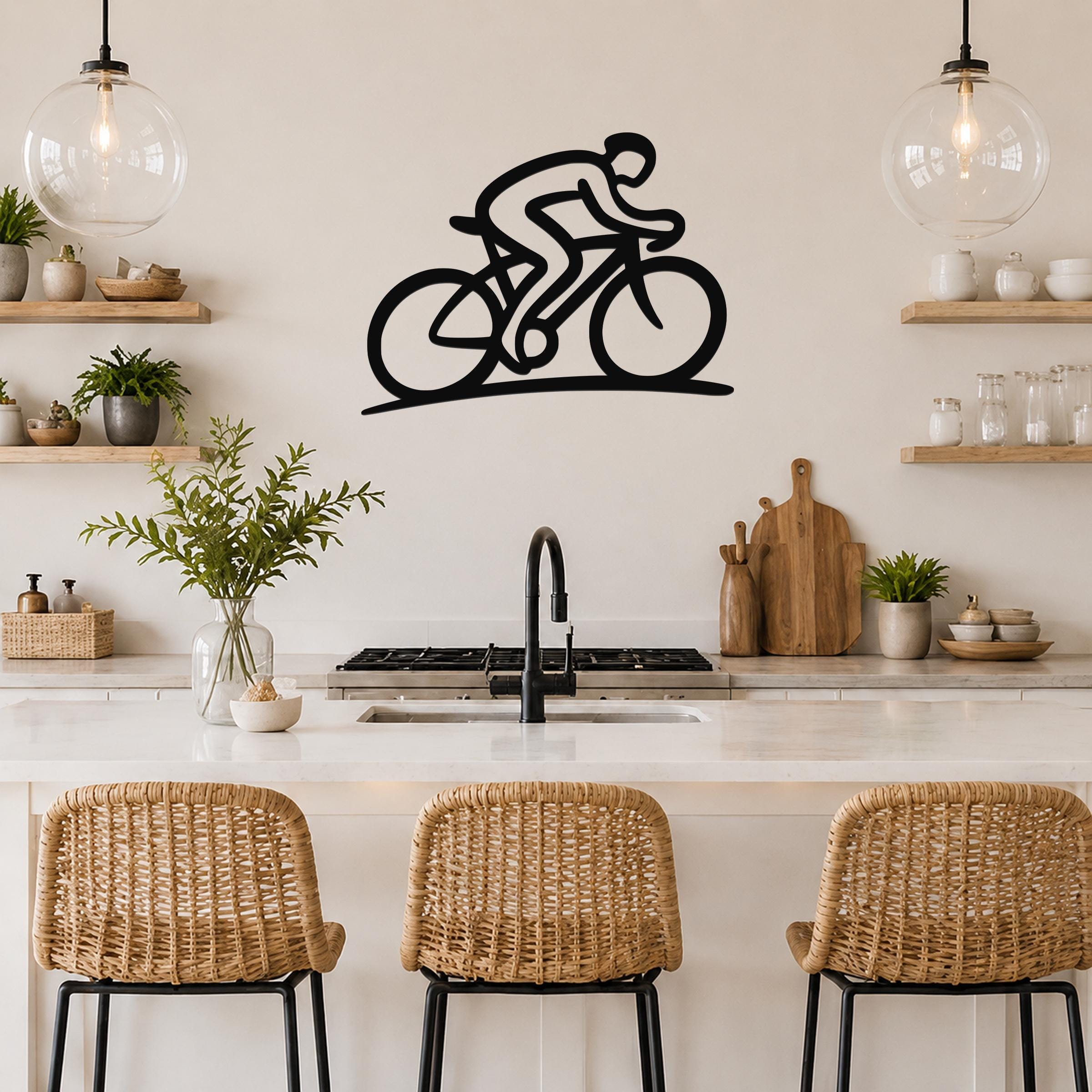 Black metal wall art featuring a dynamic cyclist silhouette with internal cutouts, mounted above a kitchen counter.