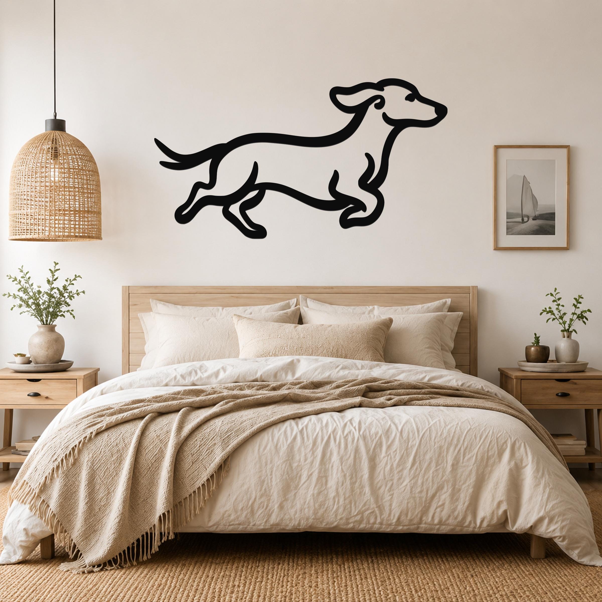 Black metal dachshund wall art with a playful running silhouette, mounted above a bed in a neutral bedroom.
