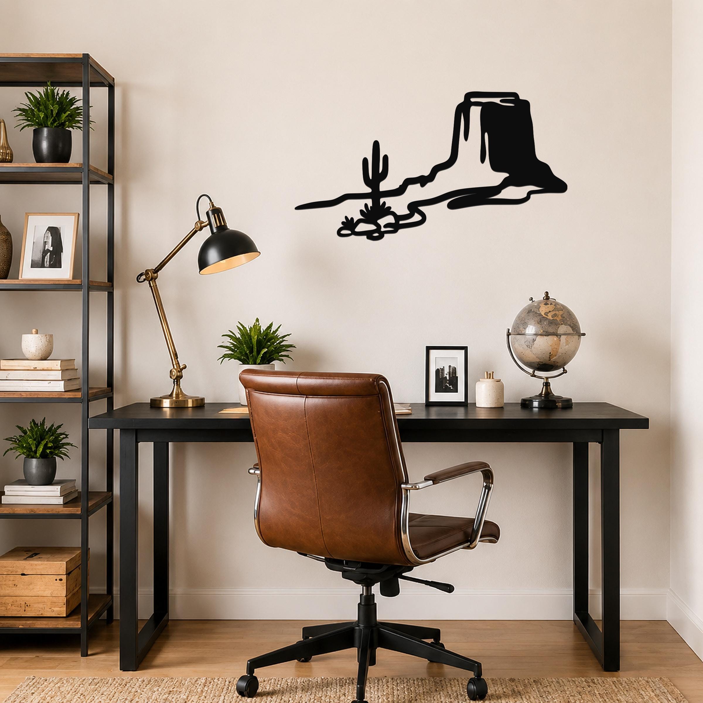 Black metal wall art silhouette of a desert mesa and cactus, mounted above a black desk in a home office.