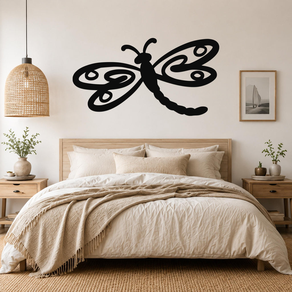 Black metal dragonfly wall art with swirling wing cutouts, mounted above a wooden bed in a neutral bedroom.