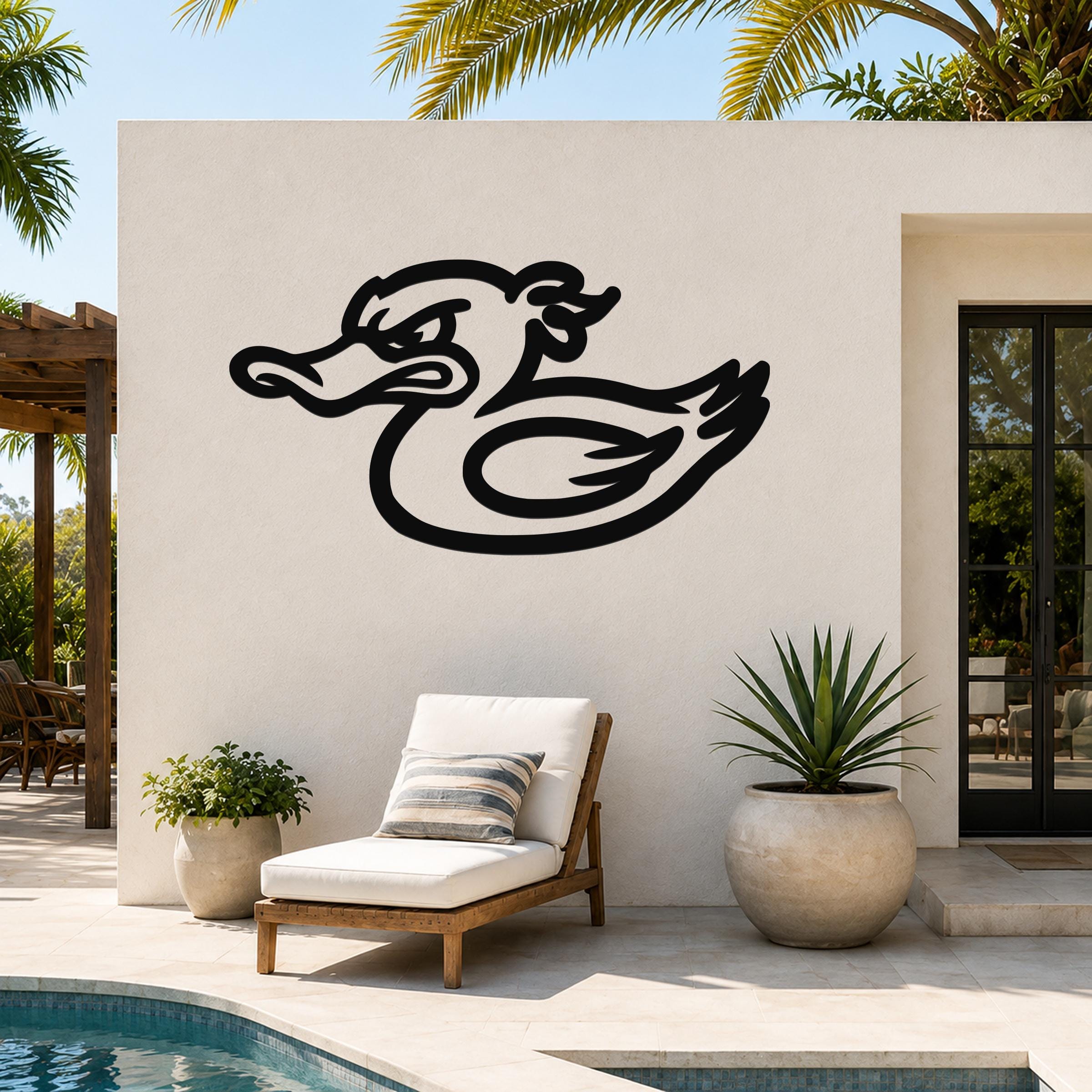 Black metal duck wall art with a bold silhouette design, mounted on an outdoor patio wall above a lounge chair and potted plants.