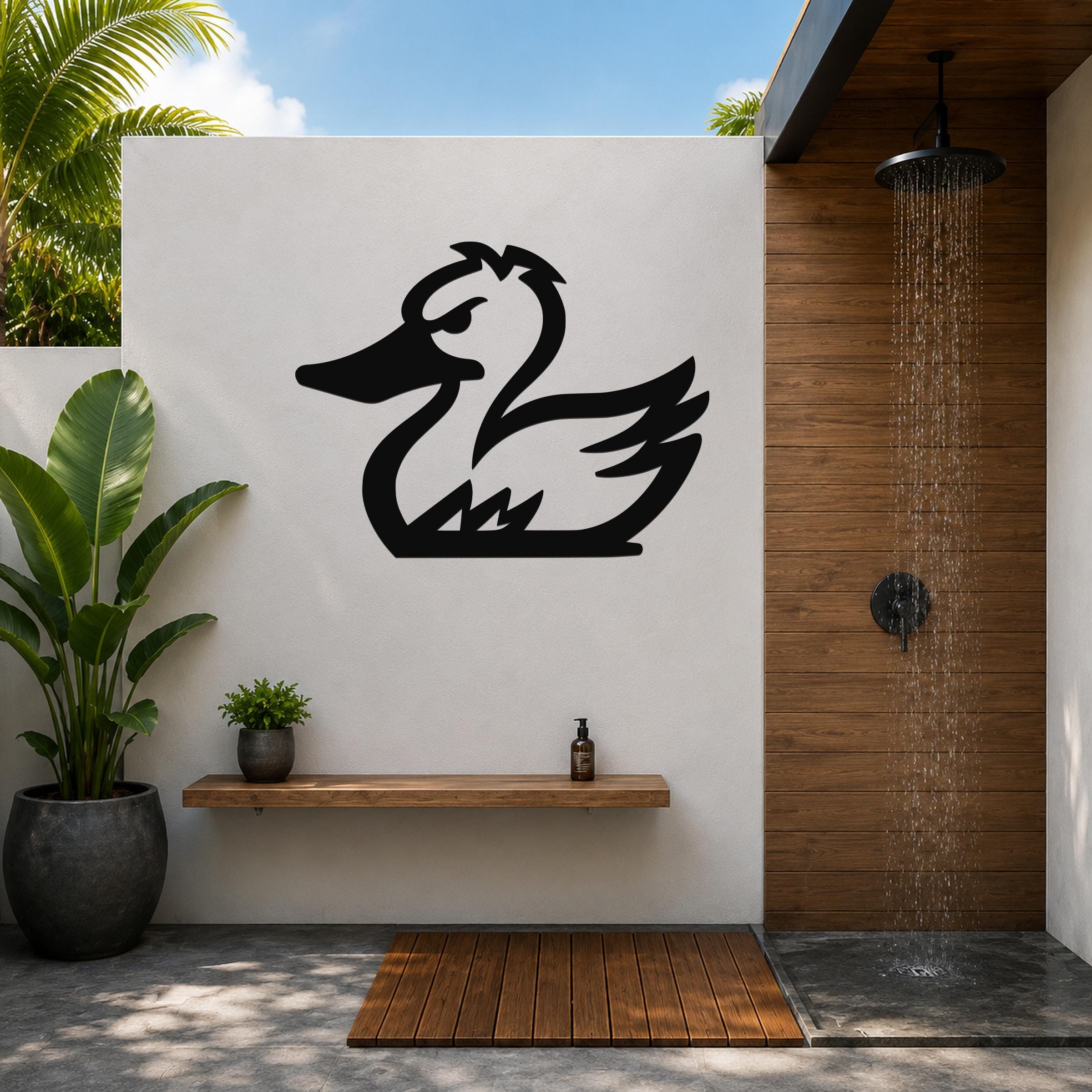 Black metal duck silhouette wall art mounted on a white outdoor wall above a wooden shelf in a modern patio shower area.